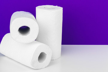 Roll of paper towel on table against purple background