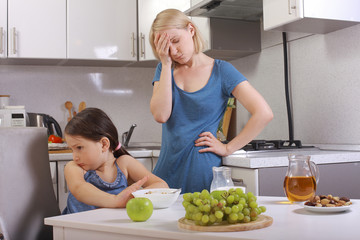  in the kitchen. mother scolding a child. a child refuses to eat, mom makes daughter eat healthy. mom and daughter are having Breakfast, the baby won't eat. quarrels, conflicts in the family