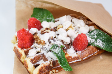Belgian waffle with fruit and powdered sugar on a white background