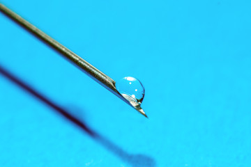 Medical Syringe needle on blue background, macro shot.