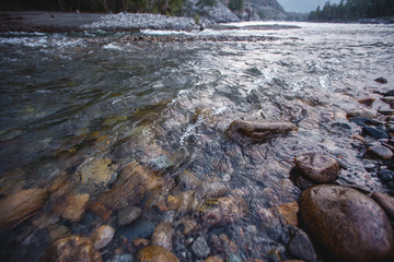 Mountain, transparent river, flowing among smooth stones. clous-up