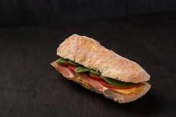 sandwich with ham and vegetables on dark board