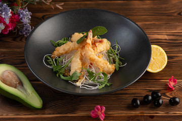 Tempura shrimps with tartar sauce on a black plate on a wooden background