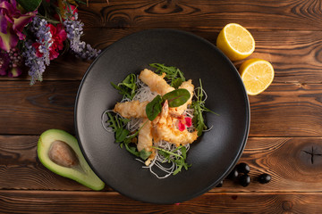 Tempura shrimps with tartar sauce on a black plate on a wooden background