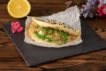 Bao with chiken on black board on wooden background