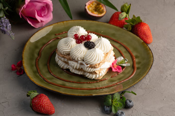 Cake with whipped cream and berries on a green plate