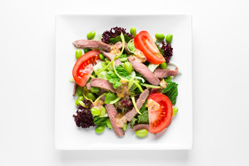 Salad with meat and tomatoes in a plate on a white background