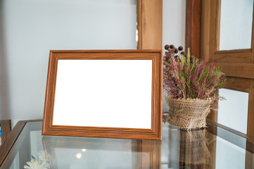 Wooden picture frame with flower decoration on glass table
