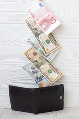 Close-Up of dollars and euros on wooden background. Wallet with dollars. Hidden revenue. illegal money