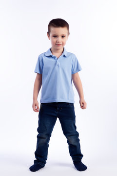 Little smiling boy with dark hair in blue jeans, blue polo t-shirt posing, laughing happily on a white isolated background in a photo studio. Portrait of happy joyful beautiful boy