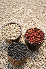 Organic white red and black pepper corns in wood display