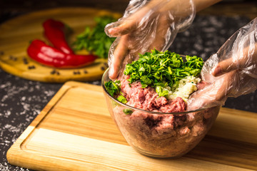 Hands mix raw minced pork in a glass bowl