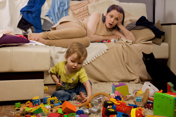 Mother sitting on the couch. Mom tired to tidy up the house. Child scattered toys. Children's room. Mess in the house