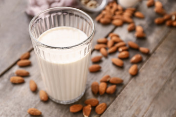 Glass of tasty almond milk on wooden table