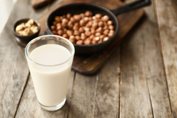 Obraz na płótnie Canvas Glass of tasty hazelnut milk on wooden table