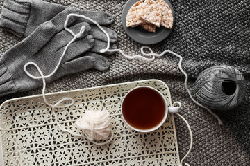 Tray with cup of hot tea, threads and crispbread on plaid