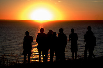 Fototapeta na wymiar Silhouettes of a group of people watching the sunset over the Volga river