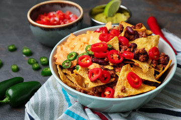 Plate with tasty nachos, minced meat and chili on table