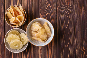 Bowls with tasty dried fruits on wooden background