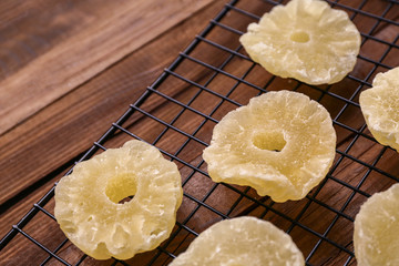 Grid with tasty dried pineapple on wooden table