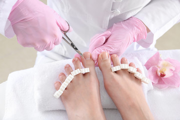 Obraz na płótnie Canvas Podiatrist cutting hard skin off feet of young woman in spa salon