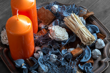 Orange candles with potpourri on an antique metal tray with a wooden background