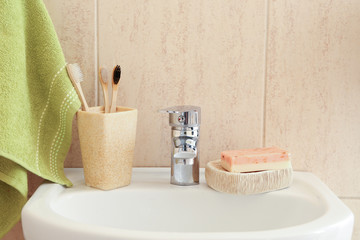 Holder with toothbrushes on sink in bathroom