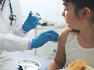 Female doctor giving an injection to a young cute girl