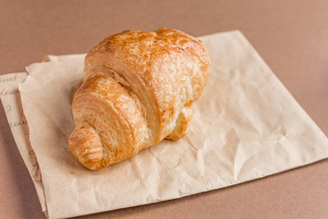 Close up of freshly baked french croissant on craft paper for breakfast.