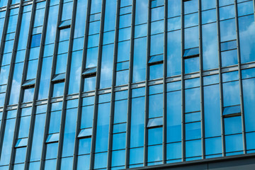 Fototapeta premium Chmury odzwierciedlone w systemie Windows w nowoczesnym biurowcu.