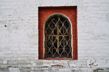 Window with grill on the background of an old brick wall