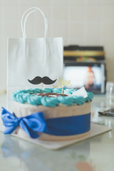 beautiful brithday cake with blue bow-knot on the desk