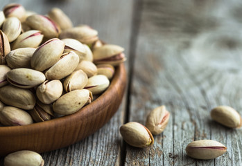Unpeeled pistachios in a wooden cedar plate