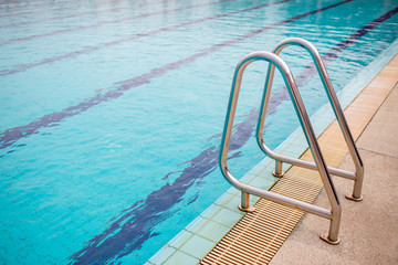 Ladder stainless handrails for descent into swimming pool. Swimming pool with handrail . Ladder of a swimming pool. Horizontal shot.