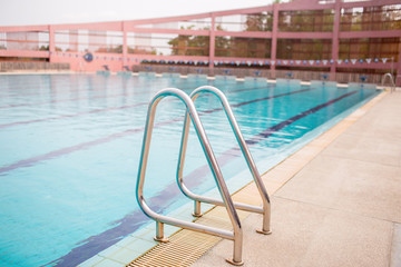 Ladder stainless handrails for descent into swimming pool. Swimming pool with handrail . Ladder of a swimming pool. Horizontal shot.