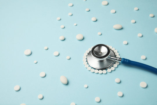 Medical stethoscope and pills on blue background. Health care.