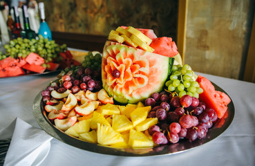 Fruit carving for wedding reception. Watermelon, peaches, grapes and pineapples are on the plate. Dessert for guests.
