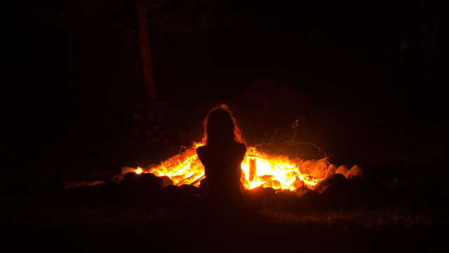 Donna di spalle davanti al fuoco del fal&ograve;