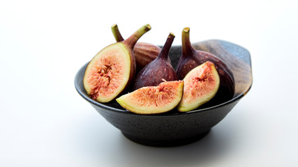 Organic figs in a bowl on white table