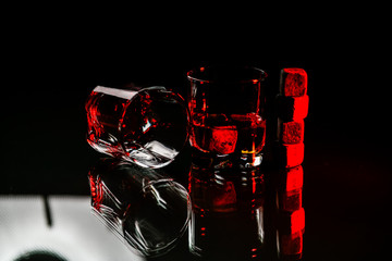 Naklejka na ściany i meble glasses made from whiskey on a glass table are isolated on a black background, special stones for whiskey. glass objects
