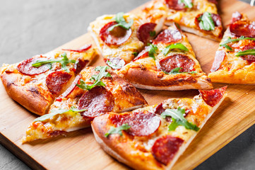 Pepperoni Pizza with Mozzarella cheese, salami, Tomato sauce, pepper, Spices and Fresh arugula. Italian pizza  on Dark grey black slate background