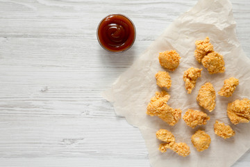 Top view, chicken bites and bbq sauce over white wooden background. Flat lay, overhead, from above. Copy space.
