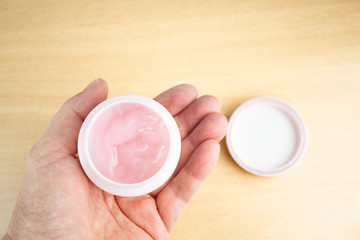 Woman holding a can with pink face cream in her hand
