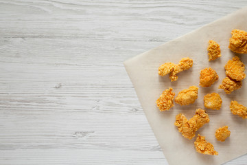 Chicken bites over white wooden surface, top view. Flat lay, overhead, from above.