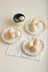 Turkey eggs in three white dishes on light dyed wooden surface. Vertical.