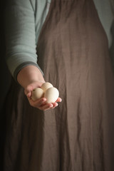 Woman holding three turkey eggs in hand. Rustic style. Vertical.