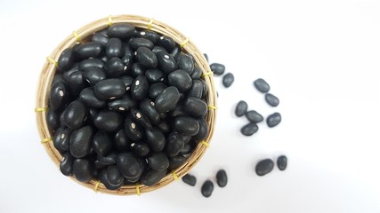 Black bean seeds in a basket with a white background. Black bean grains