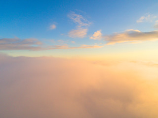 Aerial view White clouds in blue sky. Top view. View from drone. Aerial bird's eye view. Aerial top view cloudscape. Texture of clouds. View from above. Sunrise or sunset over clouds