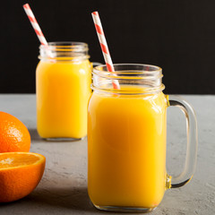 Fresh orange juice in glass jars, side view. Closeup.