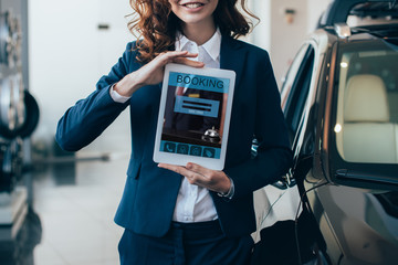 cropped view of businesswoman holding digital tablet with booking app on screen